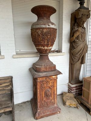 a large vase sitting on a pedestal next to a statue