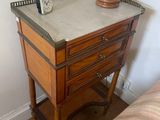a small table with a clock on top of it next to a bed