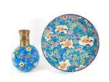 a blue plate with flowers and a small vase next to it