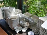 many plates and bowls sitting on a table in front of a window