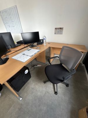 a desk with two monitors and a chair in front of it