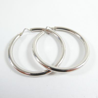 une paire de boucles d'oreilles créoles en argent sur fond blanc