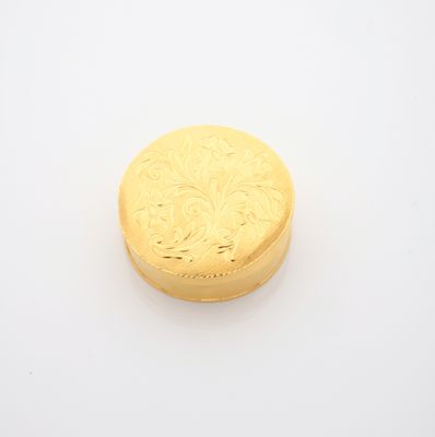 une boîte dorée posée sur une surface blanche, avec un fond blanc