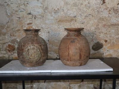 deux vases posés sur une table devant un mur de pierre