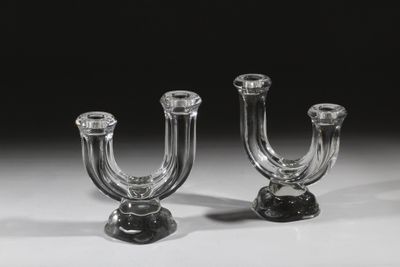une paire de bougeoirs en verre transparent posés sur une surface blanche