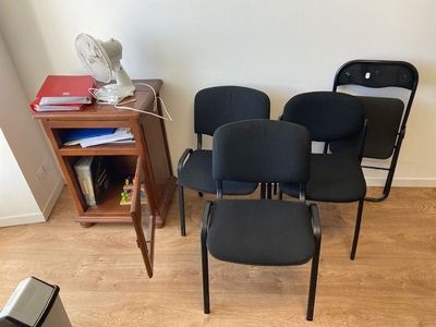 four black office chairs in a room with a fan on the wall