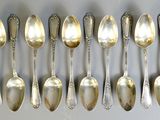 six silver spoons are arranged in a row on a white surface
