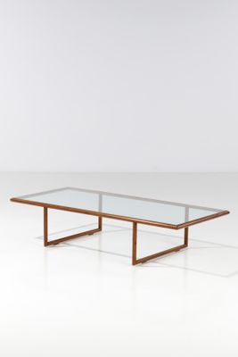 une table basse avec un plateau en verre posée sur un piètement blanc