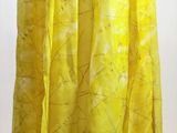 a yellow scarf hanging on a hanger in front of a white wall