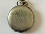 a silver pocket watch hanging from a chain on a table