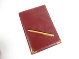 a red notebook with a gold pen on top of it