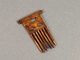a small wooden comb that has a design on it