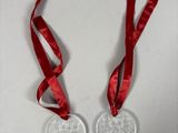 two christmas ornaments with red ribbons hanging from them on a white wall