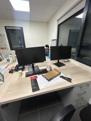 un bureau sur lequel se trouvent deux écrans d'ordinateur et un téléphone