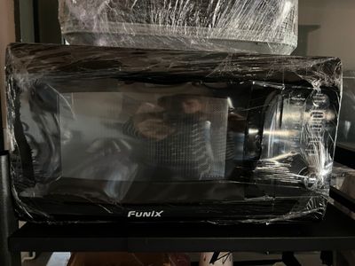 un micro-ondes posé sur une table recouverte d'un film plastique