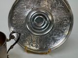 a silver plate and a silver cup on a table