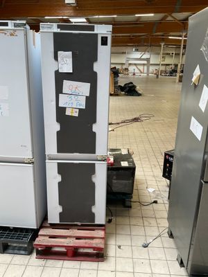 Plusieurs réfrigérateurs sont empilés sur des palettes dans un entrepôt