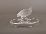 a glass bird sitting on top of a glass plate