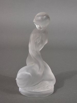 une figurine en verre représentant une femme assise sur un rocher