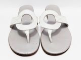 une paire de tongs blanches posées sur une surface blanche, avec un fond blanc