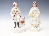 pair of porcelain figurines of a man and a woman with a dog