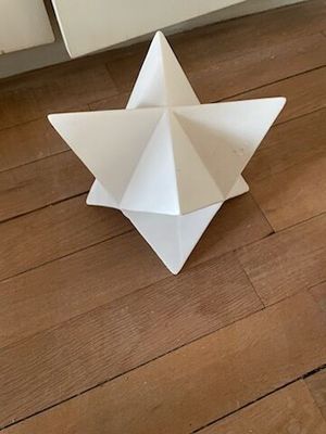 une étoile en origami blanche posée par terre à côté d'une porte