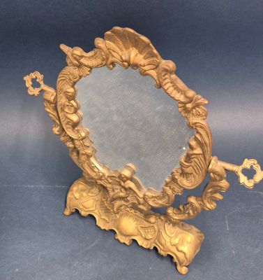 un miroir doré posé sur un pied, dans lequel se trouve une clé