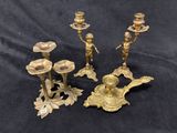 three brass candlesticks and a candle holder on a black background