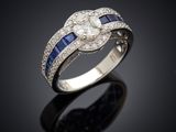 a close up of a diamond and sapphire ring on a black surface