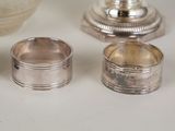 three silver napkins and a silver bowl on a table