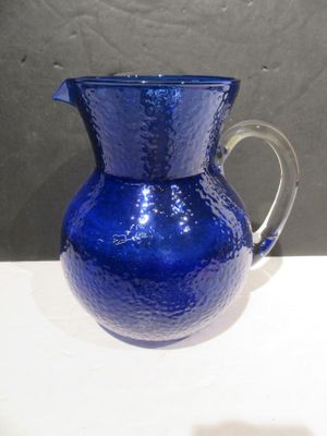 a blue glass pitcher sitting on a white table