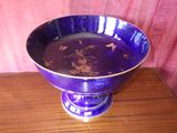 a purple bowl on a wooden table with a pink curtain in the background