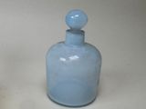 a blue glass bottle sitting on a white surface