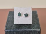 a pair of green earrings sitting on top of a marble block