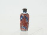 a red and blue vase sitting on top of a clear shelf