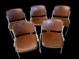quatre fauteuils en cuir marron avec des pieds en métal, sur fond noir