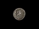 un gros plan d'une pièce de monnaie sur laquelle figure un visage, sur fond noir