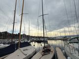 several sailboats docked at a dock in a harbor under a cloudy sky