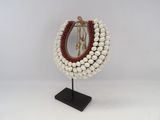 a white and red beaded necklace on a black stand