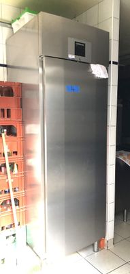 un grand réfrigérateur en acier inoxydable dans une cuisine, à côté d'une pile de caisses