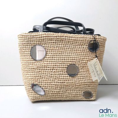 un sac en paille muni d'une étiquette, posé sur une table