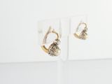 a pair of gold and silver earrings on a clear stand