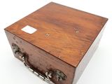 une petite boîte en bois avec des poignées en métal, posée sur une surface blanche