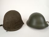 two military helmets sitting next to each other on a white surface