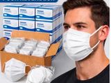 a man wearing a face mask next to a box of face masks