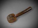 une vieille spatule en bois avec un manche en bois posée sur une surface grise