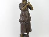 bronze statue of a woman with a bird on her shoulder
