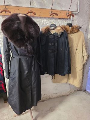 un manteau sur un mannequin devant un portemanteau rempli de manteaux