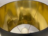 a black and gold vase with a white candle inside of it