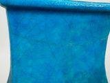 a blue vase sitting on a table with a white background